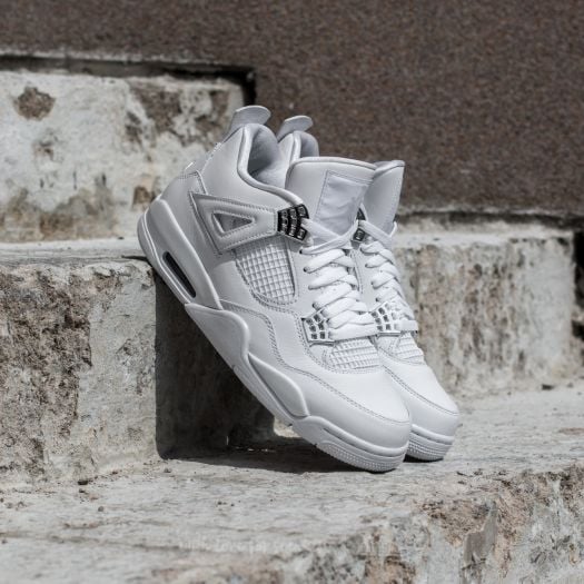 White athletic sneakers resting on rough stone steps, showcasing chunky sole design and mesh panels.