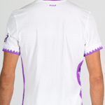 Back view of a white athletic jersey with purple trim and a purple zigzag pattern on the sleeves near the cuffs.