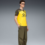 Male model wearing a yellow Borussia Dortmund jersey with Vodafone logo, olive green pants, and sunglasses, posing against a gray gradient background.