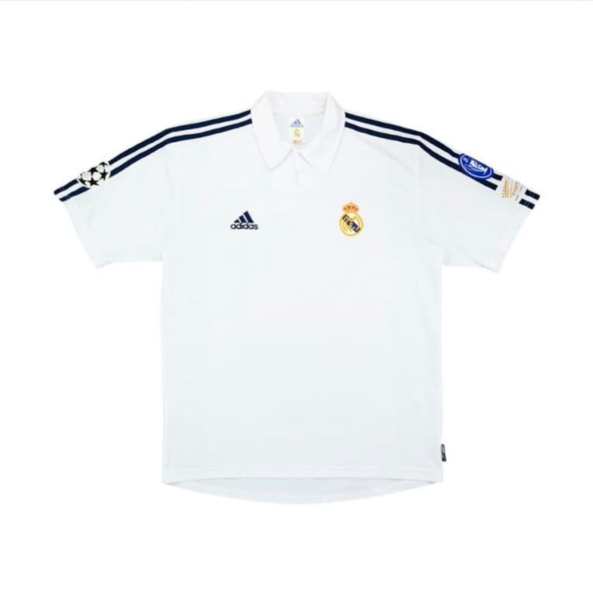 White Real Madrid football jersey with navy stripes, Adidas logo, Real Madrid crest, and Champions League badge on the sleeve.