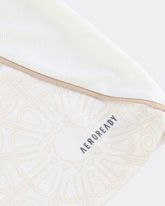 Close-up of pale patterned fabric with a beige seam and the AEROREADY branding visible at the edge.
