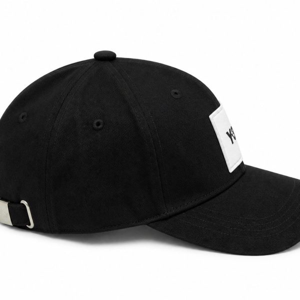 Black baseball cap with a white rectangular logo patch on the front and a metal buckle at the back for size adjustment. The cap has a curved brim.