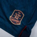 Blue fabric with a decorative badge patch reading 'Le Fil de la Paix Centenaire'.