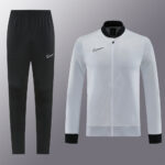Black Nike sweatpants with a small white swoosh on the hip and a white zip-up jacket with black collar and cuffs, set against a gray backdrop.