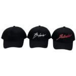 Three black Balmain baseball caps with signature embroidery in gray, white, and red.