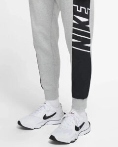Person wearing gray joggers with a black side panel and white Nike sneakers.