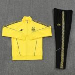 Yellow Borussia Dortmund track jacket with matching black pants; jacket features BVB 09 crest, three stars, and patterned shoulders, with Puma branding on chest and pants leg stripe.
