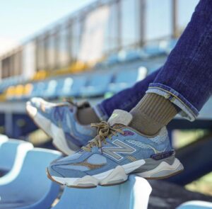 e2d85dcc-5d72-4748-b4fc-ead94d04c736 | UAE SPORT STORE Blue and gray athletic sneakers resting on light blue stadium seats, with jeans cuffs and brown socks visible.