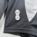 e3ccb3ce_d331ecfc-eac6-4b00-9347-d9462c632dc9 | UAE SPORT STORE Close-up of a dark textured blazer lapel with a small clear security tag attached to the fabric at the center.