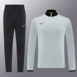 Nike tracksuit: black tapered pants with small white swoosh and a light blue long-sleeve pullover with a half-zip collar and black cuffs (product image)