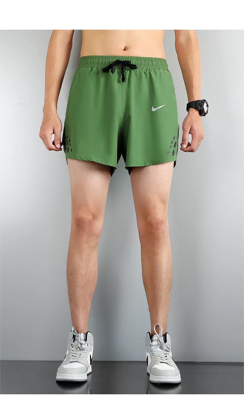 e41faf31 | UAE SPORT STORE Male model wearing green Nike athletic shorts with black drawstring, white sneakers, and a black wristwatch; side panels feature small dotted accents.