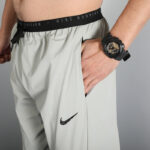 Close-up of a person wearing light gray Nike running shorts with a black waistband, hand in the side pocket, and a black sport watch visible on the wrist.