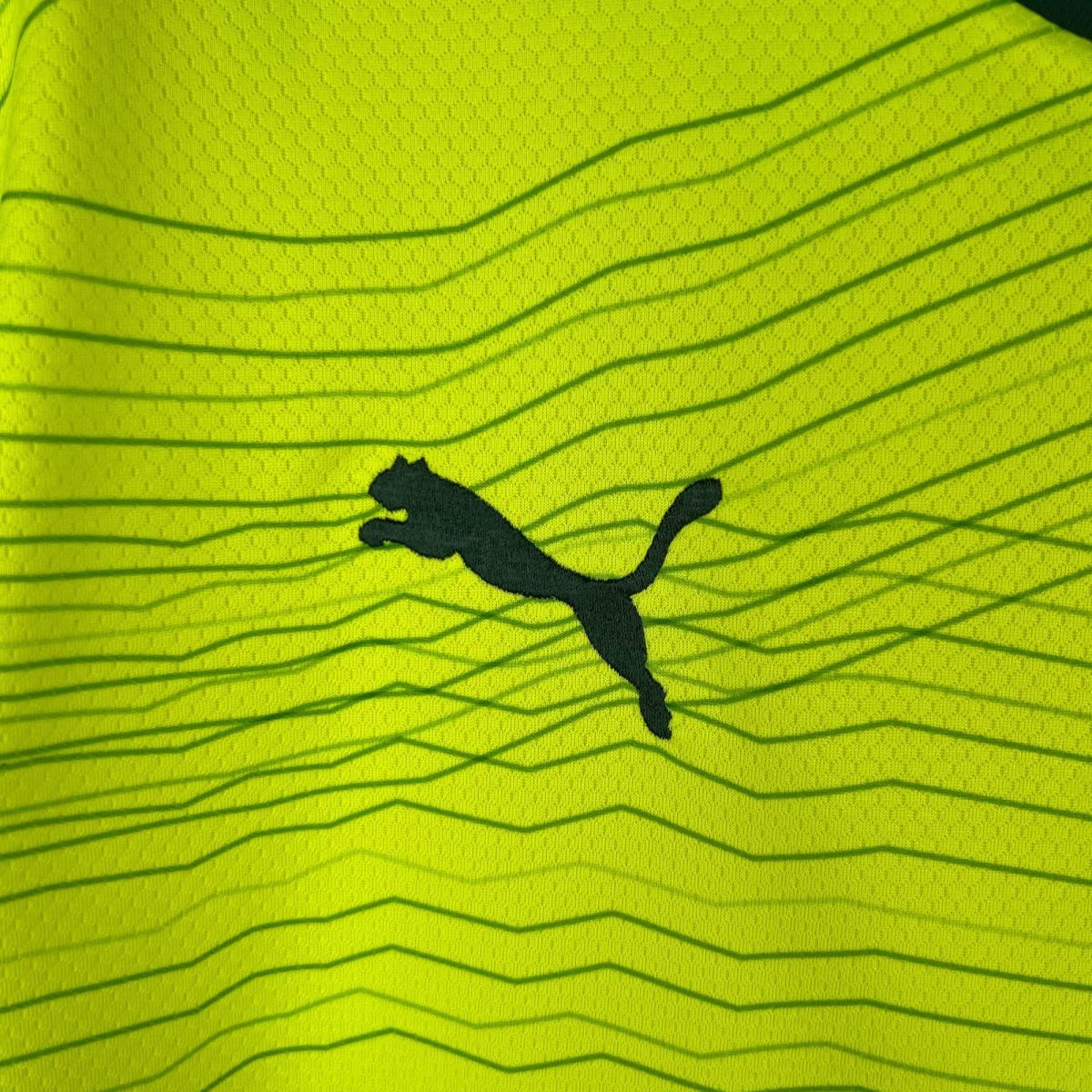 Close-up of neon yellow fabric with dark wavy lines running diagonally and a black irregular blot in the lower center.