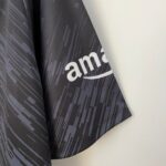 Close-up of dark gray fabric with a diagonal line pattern and partial white lettering along the edge.