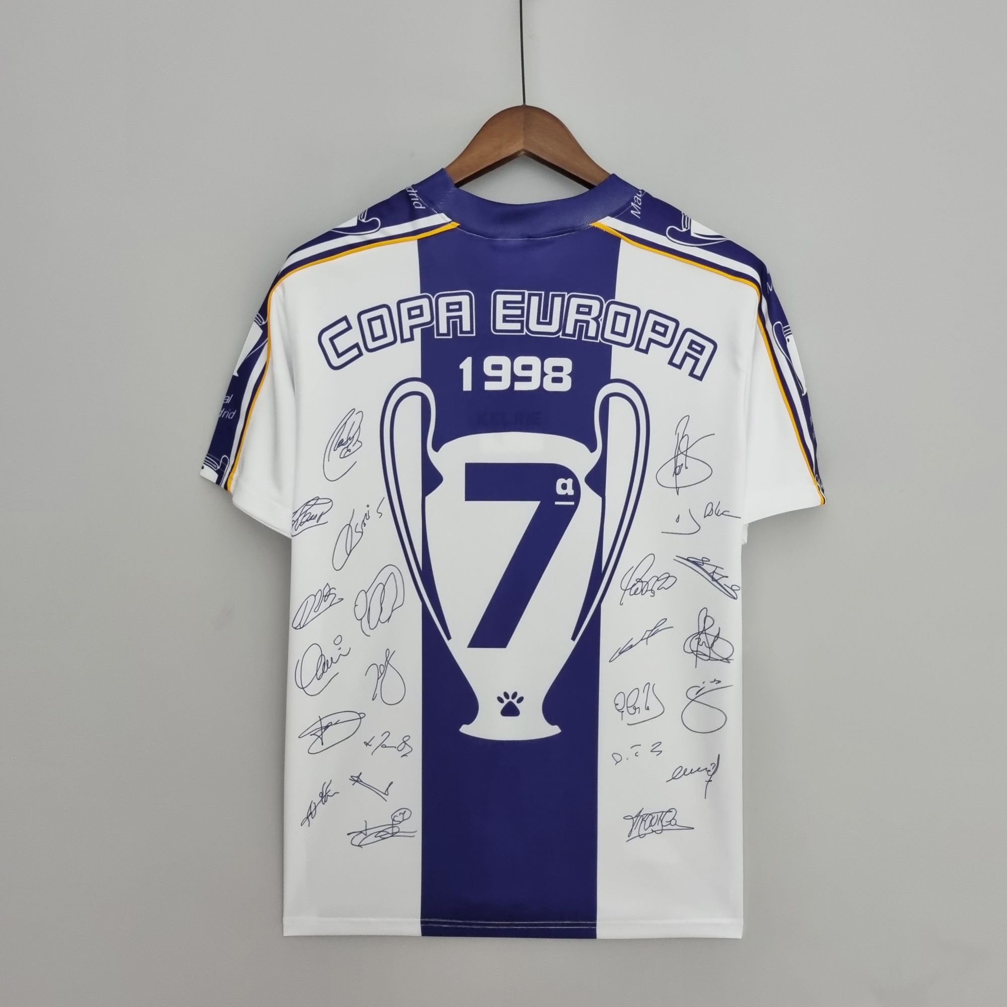 e59a87d1_11525139-27c8-4b4f-a412-3db6f797e2f2 | UAE SPORT STORE Autographed blue-and-white football jersey on a wooden hanger, displaying 'COPA EUROPA 1998' text and signatures.