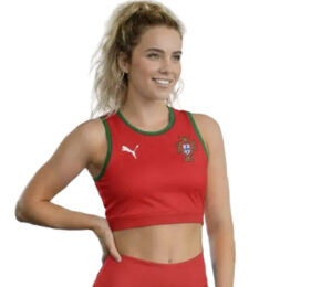 e618aaf5-76e1-4700-9dec-e093c1a49505 | UAE SPORT STORE Female athlete wearing a red Portugal crop top with green trim and crest, smiling with hand on hip.