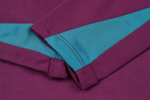 Close-up of a purple fabric with a teal diagonal stripe and folded cuff, showing stitching details.