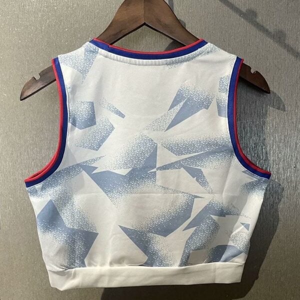 Back view of a white sleeveless sports jersey with a light blue geometric pattern and blue/red trim, hanging on a wooden hanger.