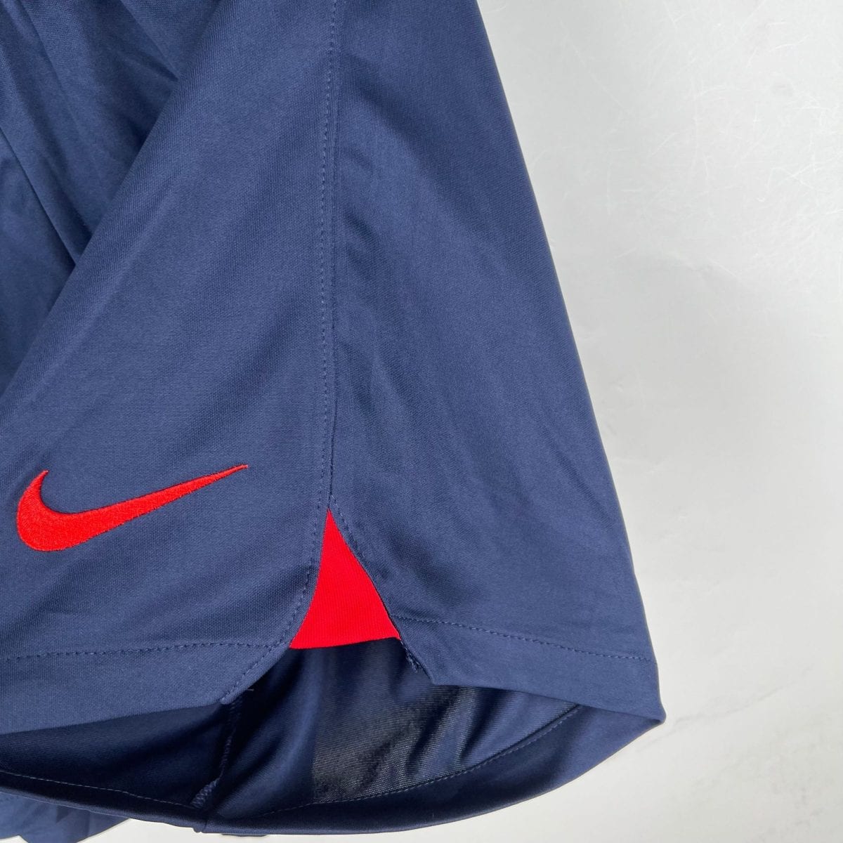 Close-up of dark blue fabric with a red Nike swoosh logo visible near a seam.