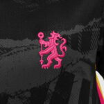 e6be26a0_3aa5_46e5_893f_914d7d419d05 | UAE SPORT STORE Pink embroidered heraldic lion holding a staff on a dark patterned fabric, likely a team logo on a jersey.