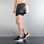 e743c9d7 | UAE SPORT STORE Side view of a person wearing dark athletic shorts with a towel tucked at the hip, and black Nike sneakers.