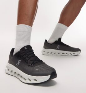 Black On running shoes with a white chunky sole, worn with light gray socks, shown from the side and front for product display