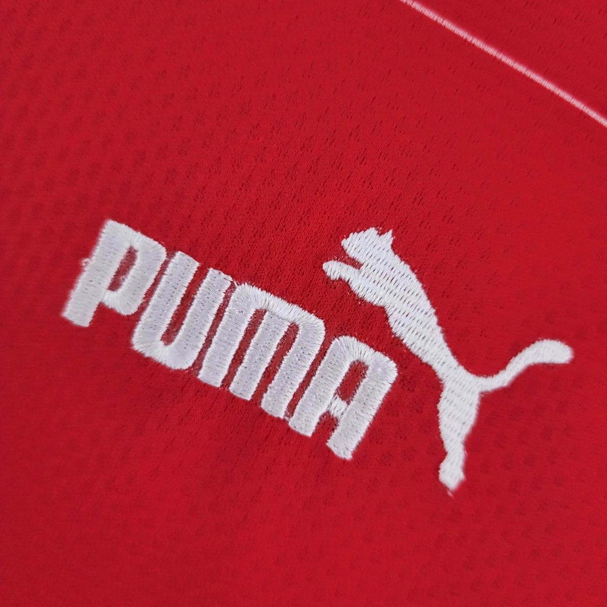 Close-up of red fabric with white embroidered letters forming part of a logo/logo text