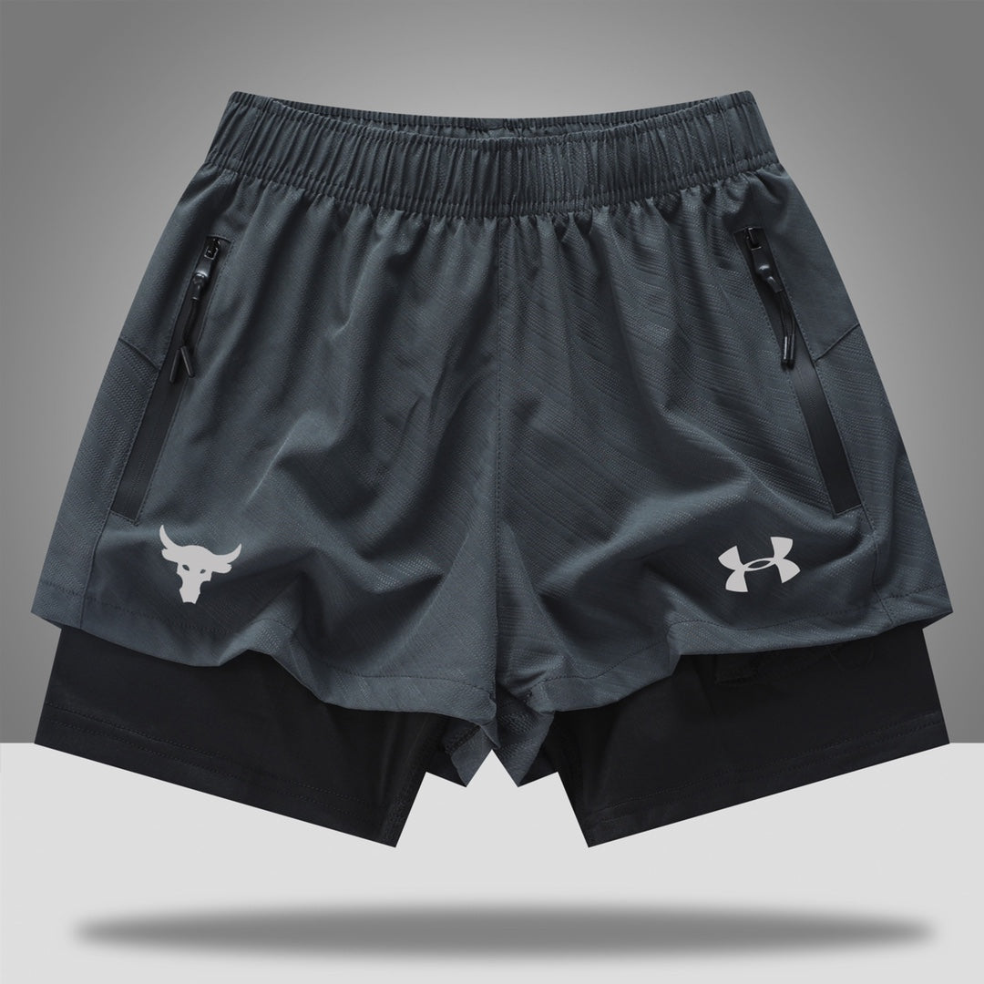 e7e8fe88 | UAE SPORT STORE Gray athletic shorts with zip pockets, layered over black compression shorts; bull head logo on left leg and Under Armour emblem on right.