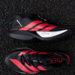 Pair of black and red running shoes with white midsole, shown on dark textured surface; features bold red stripes and 'LIGHTSTRIKE PRO' label on sole edge.