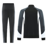 Back view of a two-tone athletic tracksuit: black jacket with gray sleeves and white cuffs, paired with black pants with gray side panels.