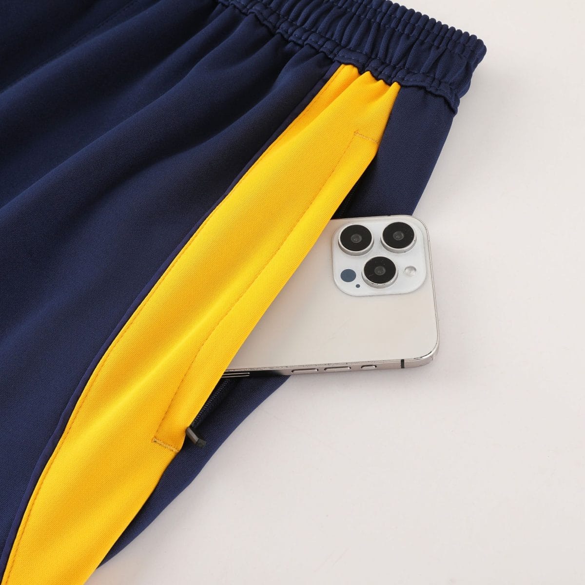 Close-up of dark navy fabric with a bright yellow stripe and a smartphone partially in view at the bottom corner.