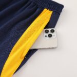 Close-up of dark navy fabric with a bright yellow stripe and a smartphone partially in view at the bottom corner.