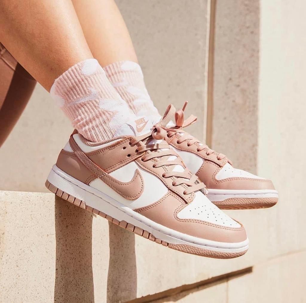 e94c2a50-f6b3-403d-9ded-dcfdeddfaaa3 Rose-pink and white sneakers with pink laces, worn with pink patterned socks, perched on a stone ledge.