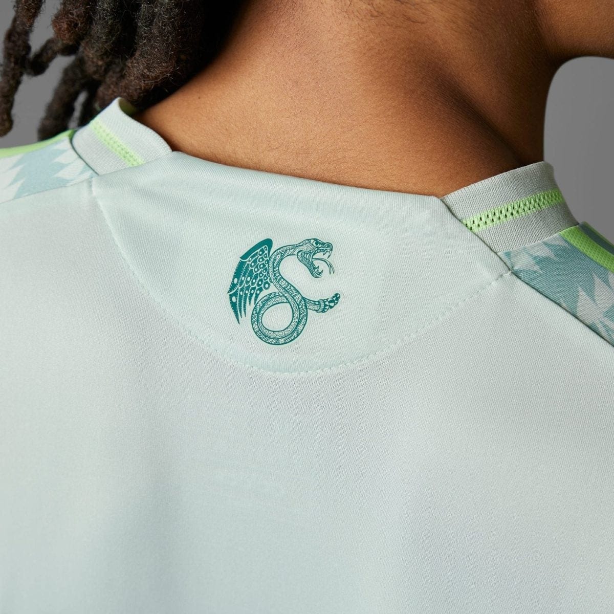 Close-up of a pale blue athletic shirt collar with a teal dragon emblem on the back near the neck area.