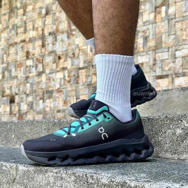 Person wearing teal and black On running shoes with white socks stepping on concrete stairs.