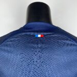 Back of a black mannequin head wearing a blue textured garment, with a small French flag sticker at the collar.