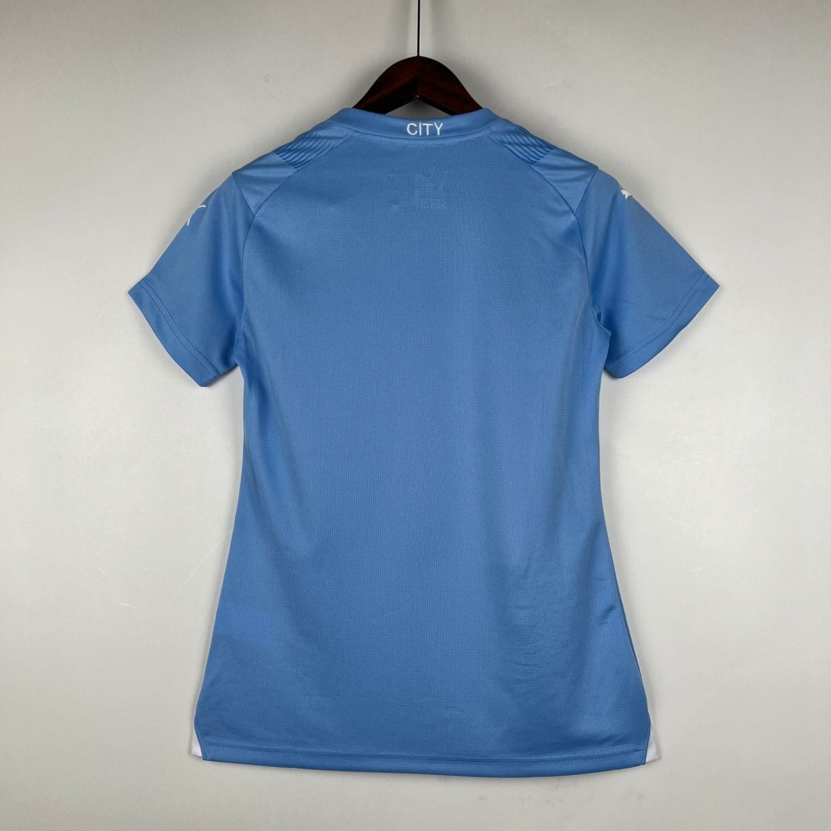 Back view of a blue polo shirt on a hanger, with 'CITY' printed on the collar.