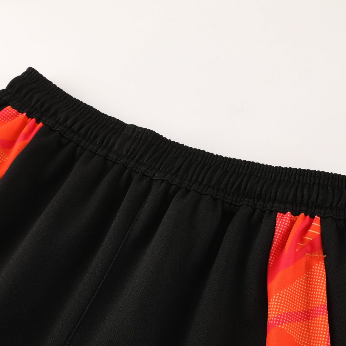 Close-up of black fabric with an elastic waistband, with a red patterned stripe along the side edge.