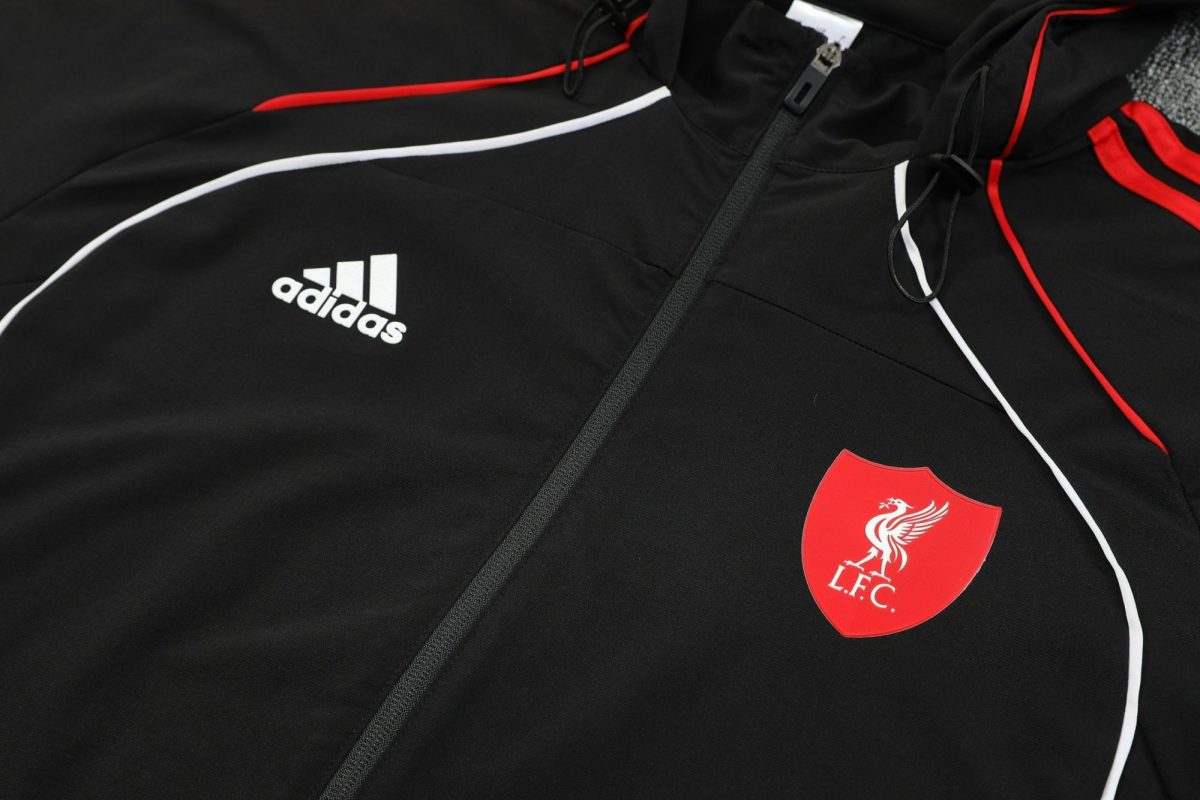 Black athletic jacket close-up with white Adidas logo and a red Liverpool FC crest near the zipper area.