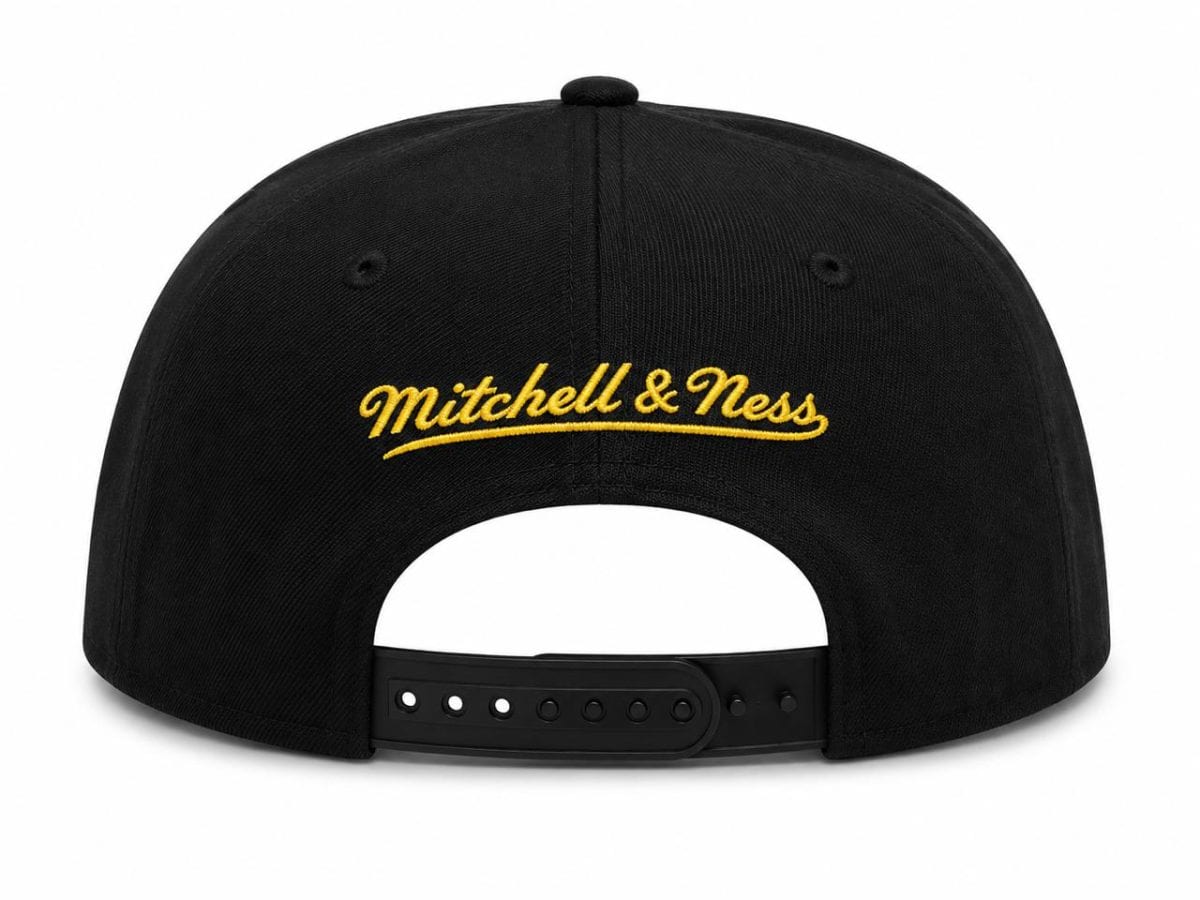 Back view of a black snapback cap with a yellow stitched "Mitchell & Ness" logo and an adjustable plastic strap