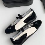 Two-tone Puma slip-on sneakers (black with white accents) placed on a light surface beside a black Puma bag, visible logo on the toe.