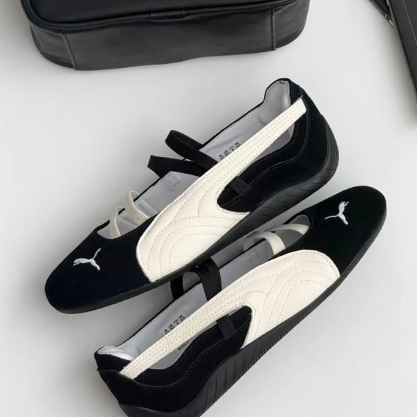 Two-tone Puma slip-on sneakers (black with white accents) placed on a light surface beside a black Puma bag, visible logo on the toe.