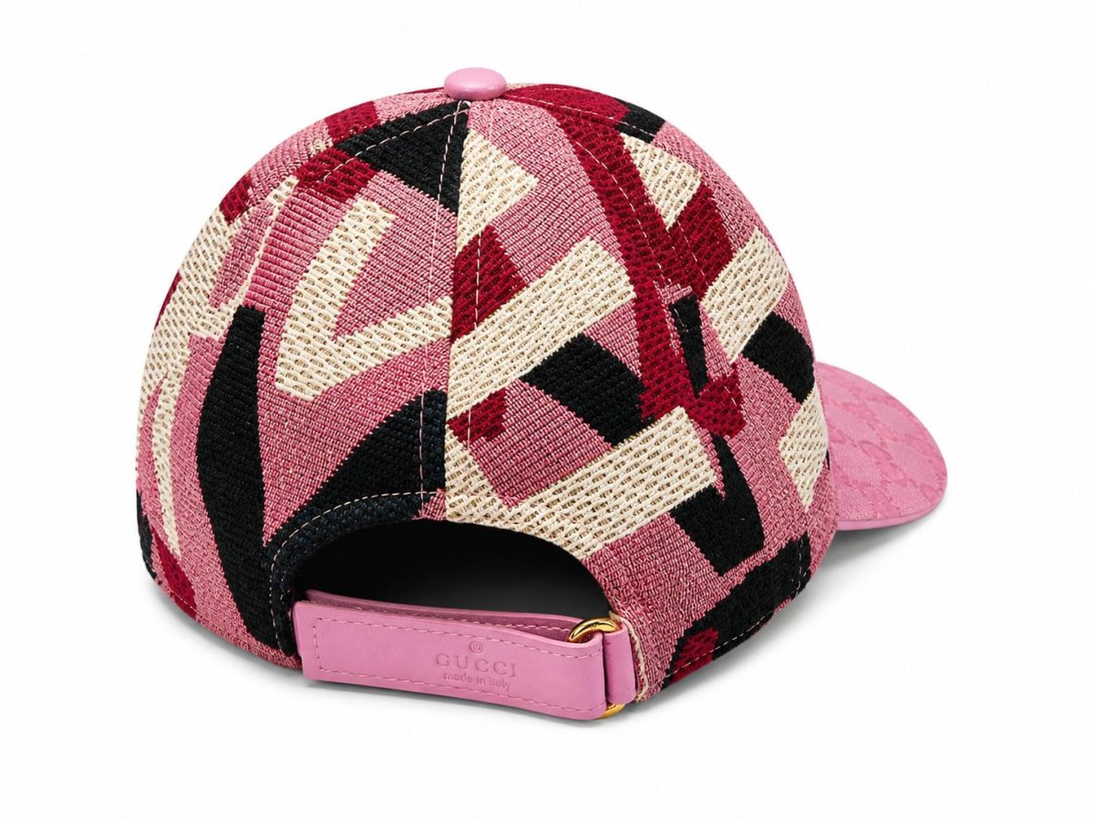 Back view of a pink quilted cap with geometric red, black, and cream panels and a pink strap featuring a Gucci label.