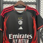 Black football jersey on hanger with red stripes, crest, three gold stars, and 'Emirates Fly Better' slogan visible