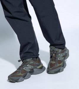 eee1f7ab-736d-4b8d-aadc-e809720e941b | UAE SPORT STORE Person wearing dark pants and gray-green hiking sneakers with a prominent 'N' logo.