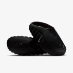 Pair of black slip-on sandals with textured uppers and ribbed straps, featuring a small Nike swoosh on each shoe.