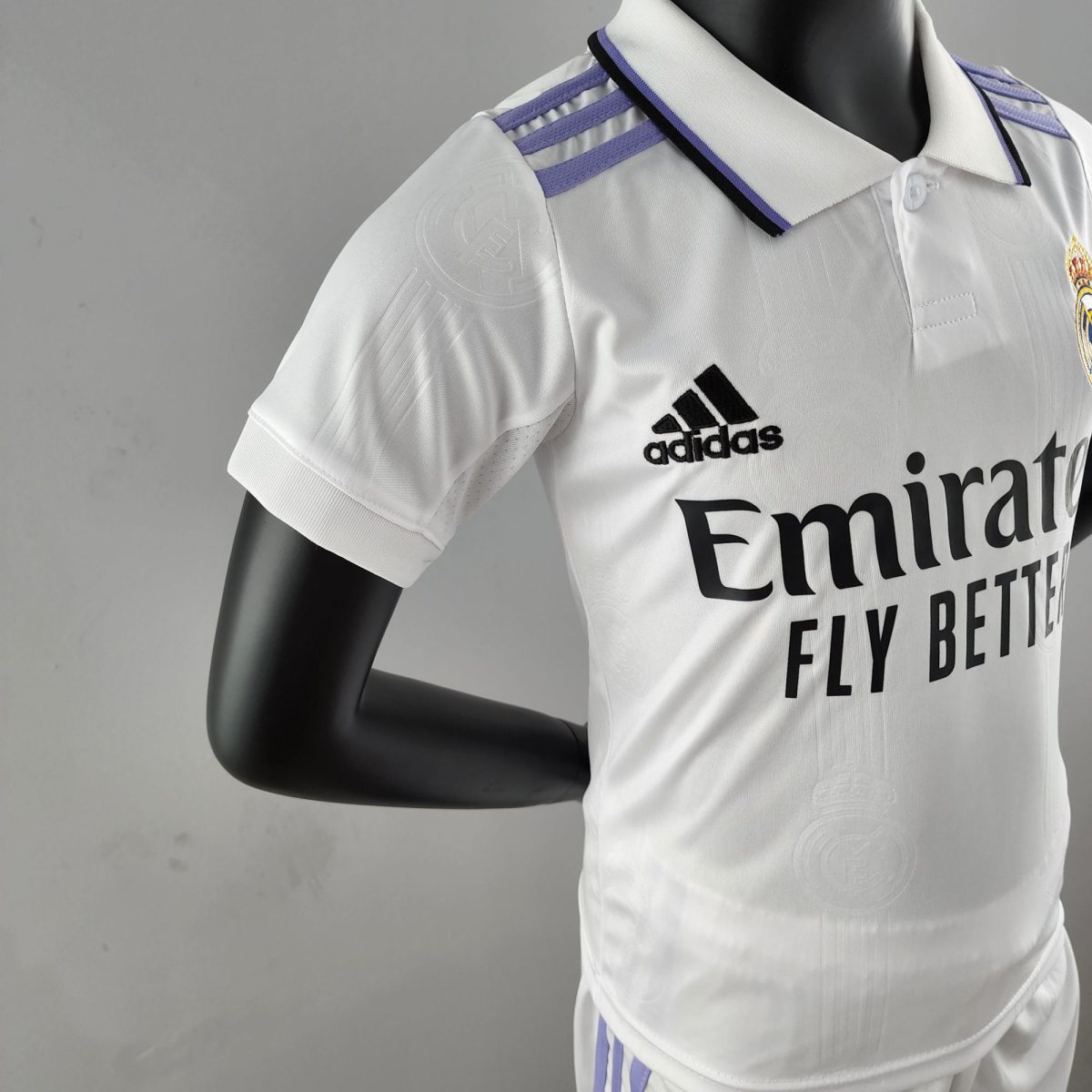 Close-up of a white sports polo with purple shoulder stripes and Adidas logo on the chest area, on a black mannequin.