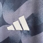 Close-up of blue denim fabric with white stitching forming a jagged chevron pattern.