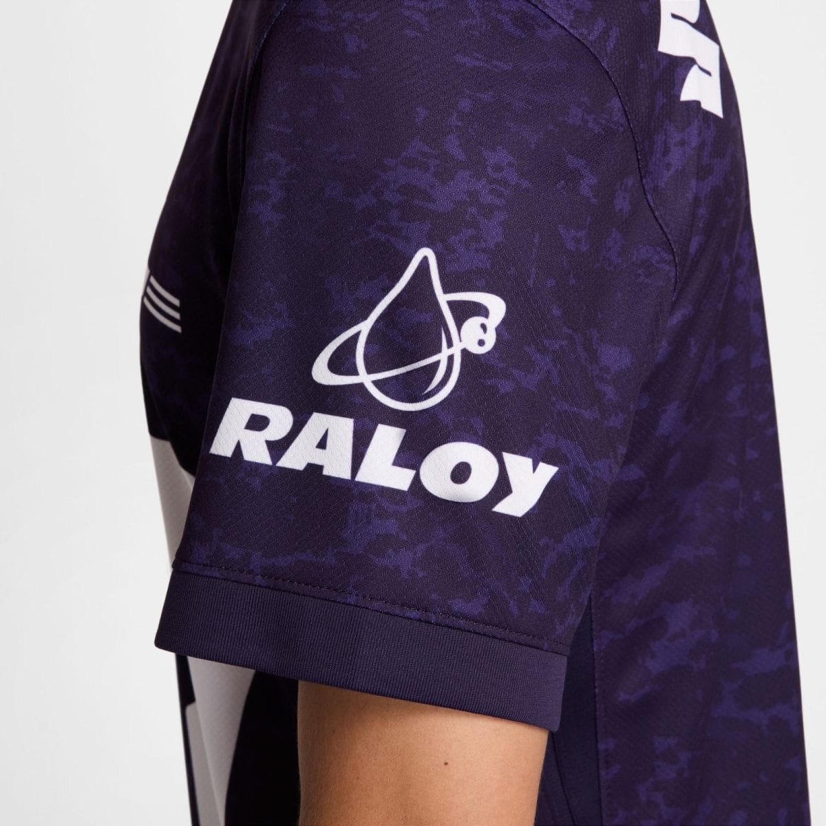 Close-up of a purple camouflage-pattern sports jersey sleeve featuring a white brand logo and the word 'RALOY'.