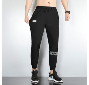 Black athletic joggers with a drawstring waist and a white Nike swoosh patch on the lower left leg, paired with black sneakers.